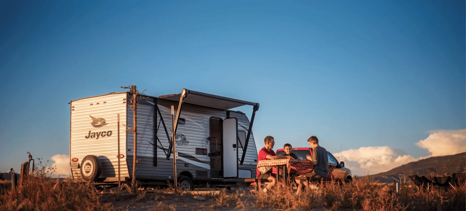 Family camping with a Jayco trailer at sunset
