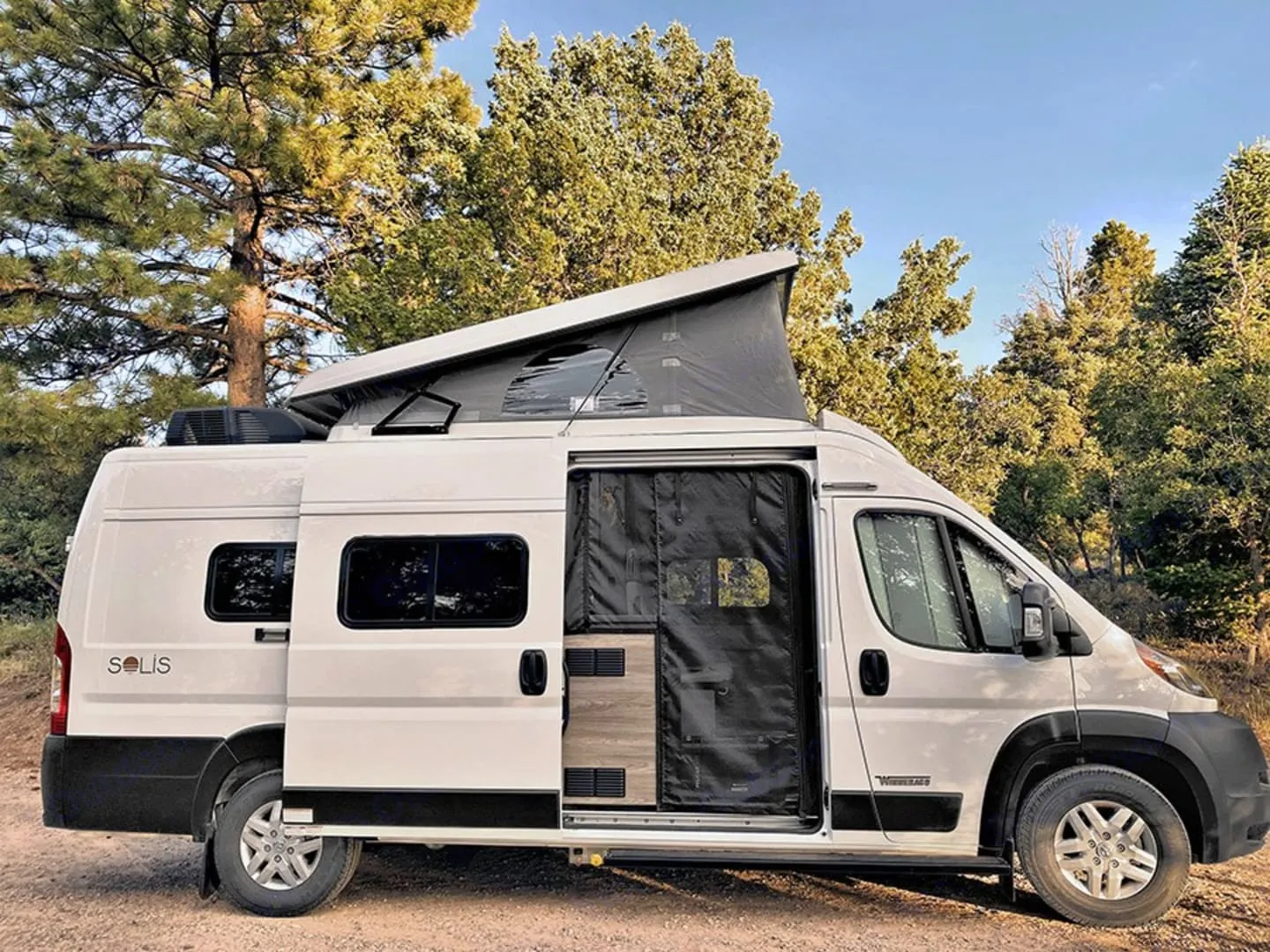 Winnebago Solis campervan with pop-top roof among pine trees