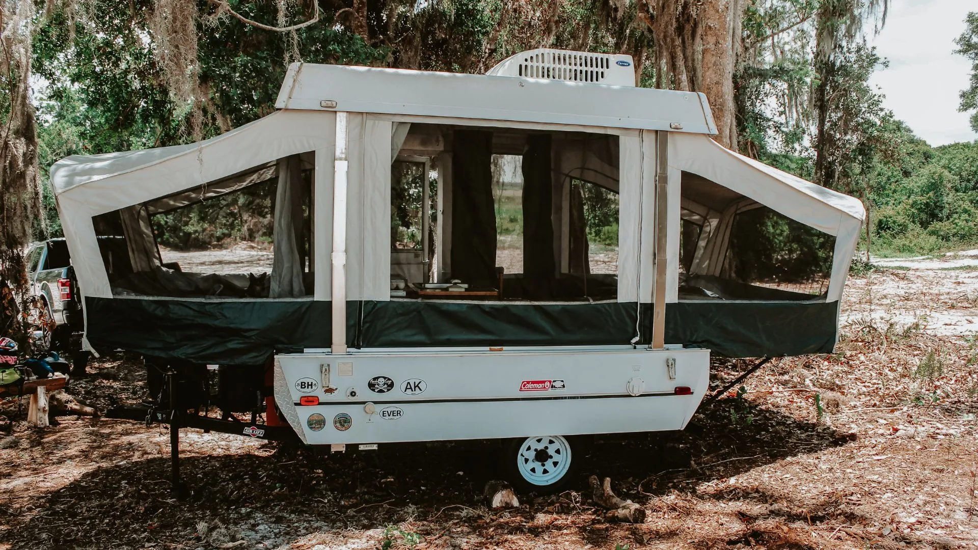 Popup camper set up at a shaded campsite